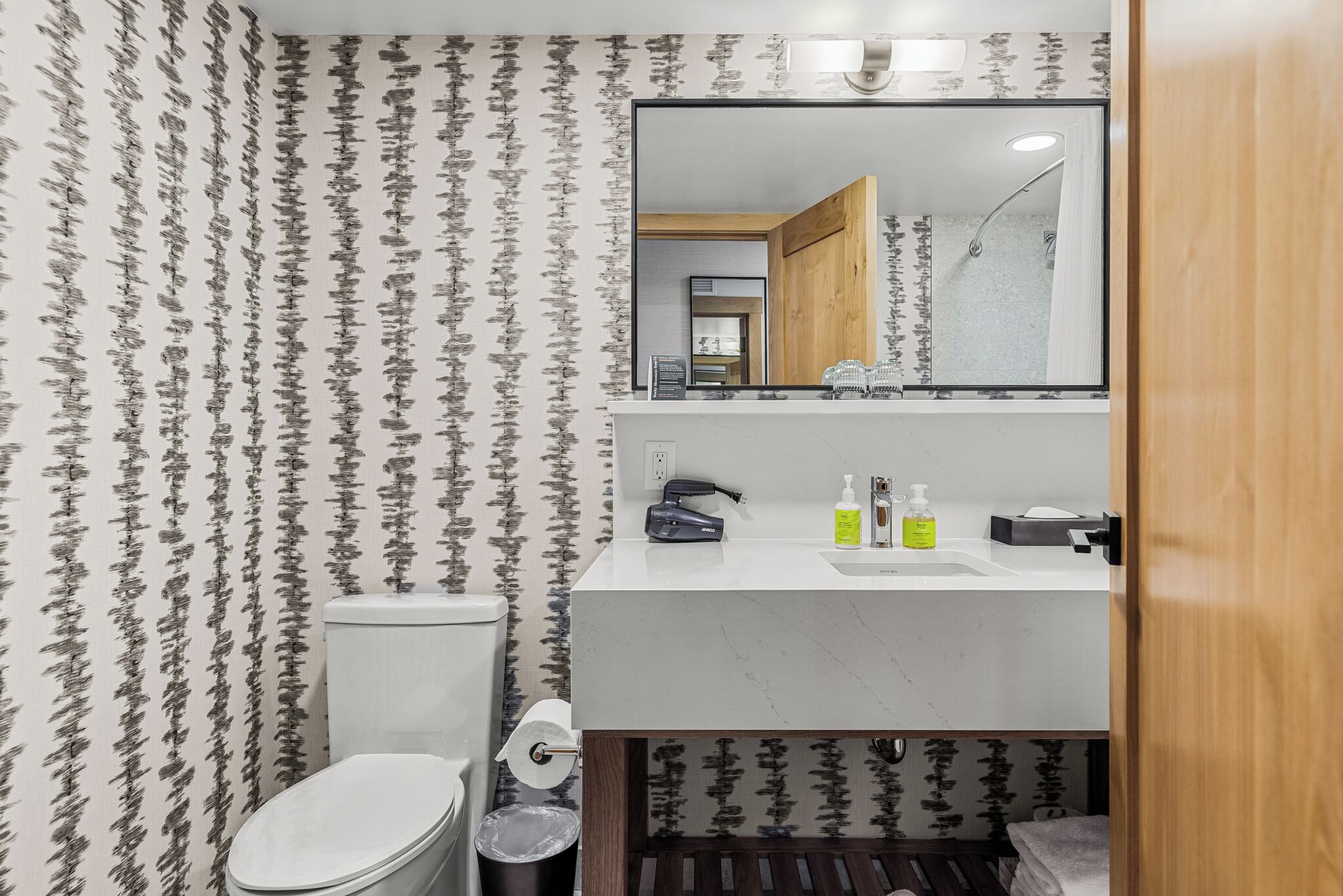 Une salle de bain avec des toilettes, un lavabo et un miroir.