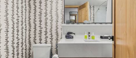 A bathroom with a toilet, sink, and mirror.