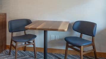 Una habitación pequeña con una mesa de madera y dos sillas azules. Encima de la mesa, hay dos palas decorativas en la pared.