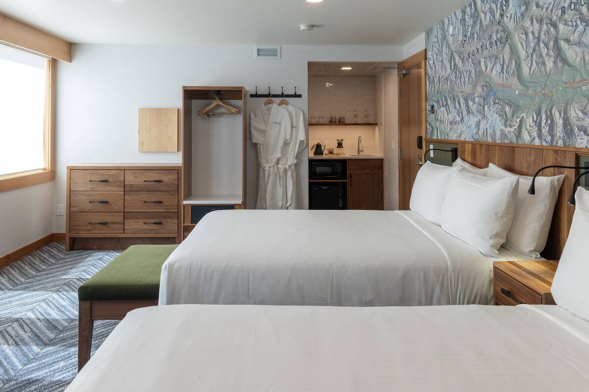 A hotel room with a large bed, a wooden dresser, a robe hanging on a rack, and a map on the wall.