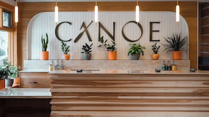 A reception desk with the word "CANOE" in large letters, surrounded by potted plants.