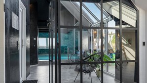 Ein modernes Interieur mit Glastür zum Poolbereich, inklusive Stuhl und Topfpflanze.