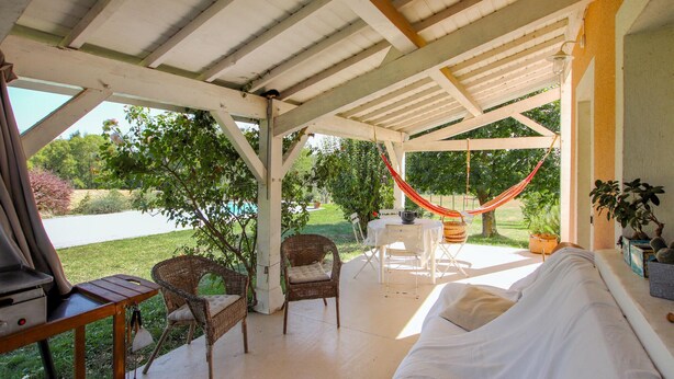 A covered outdoor seating area with wicker chairs, a white sofa, and a hammock. - Stunning home in Monseveroux (Monseveroux)