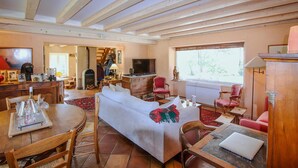 A cozy living room with a sofa, chairs, a dining table with glasses, a fireplace, and a television. - Stunning home in Monseveroux (Monseveroux)