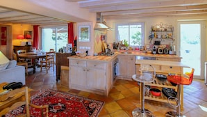 A spacious kitchen with a central island, wooden cabinets, and a dining area with a table and chairs. - Stunning home in Monseveroux (Monseveroux)