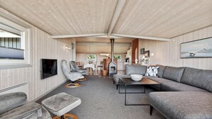 Un interior acogedor con un sofá gris, dos sillones, una mesita y una chimenea.