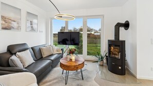 A modern living room with a black sofa, a wooden coffee table, and a black wood-burning stove.