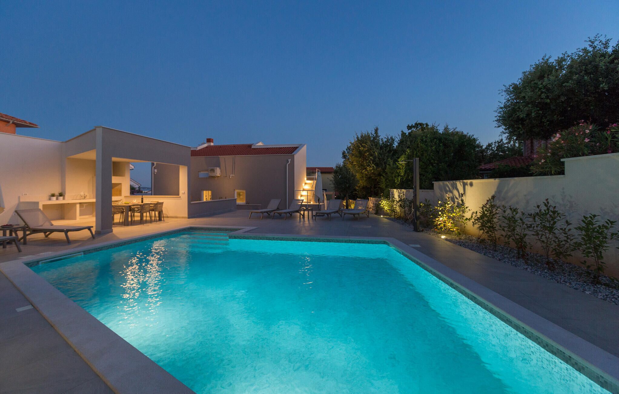 Un área de piscina moderna con sillones de descanso y una zona de bar.