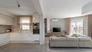 A modern kitchen with integrated appliances, a dining area with a flat-screen TV, and a living room with a sofa and a balcony view. - Beautiful home in Barbariga (Barbariga)