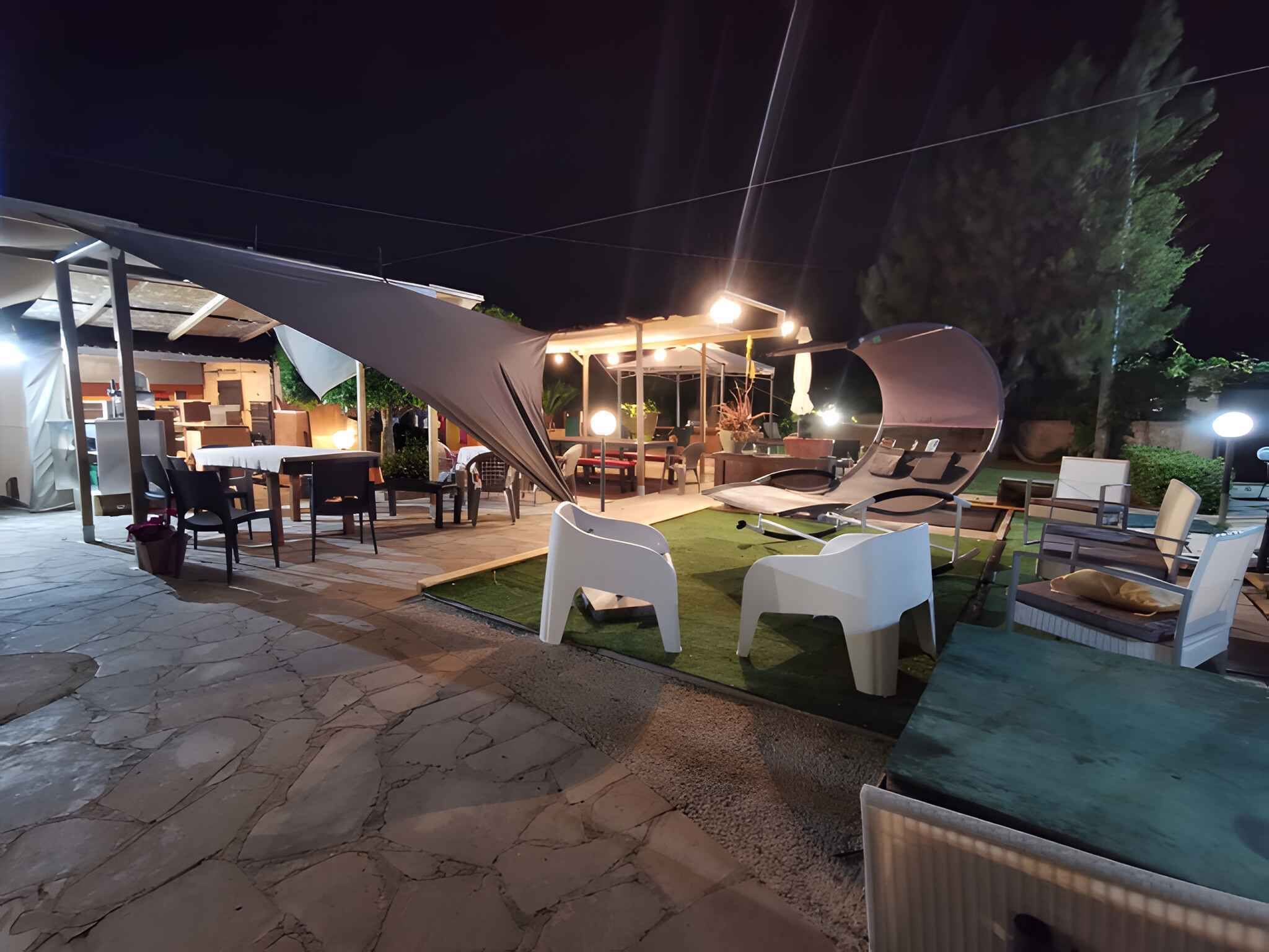 Un espace extérieur aménagé en terrasse, avec un sol en pierre, des chaises en plastique blanches et une table à manger.