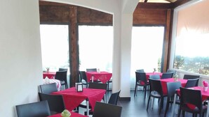 A restaurant with tables covered in red tablecloths and black chairs, large windows, and a tiled floor. - Holiday home in a quiet location (Modica)