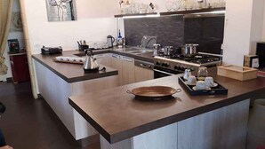 A modern kitchen with a central island, stainless steel appliances, and a variety of kitchenware. - Holiday home in a quiet location (Modica)