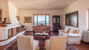 A living room with a fireplace, a sofa, a coffee table, and a view of the mountains. - Holiday home with a/c (Dorgali)