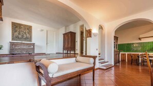 A spacious kitchen with a dining area, a bench, and a staircase leading to another level. - Holiday home with a/c (Dorgali)