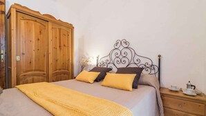 A bedroom with a bed, wooden wardrobe, and a nightstand with a cup and saucer. - Villa in a quiet location (Cala Gonone)