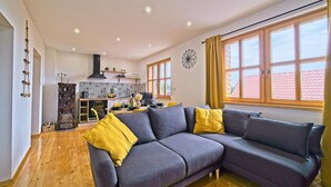 A modern living room with a grey sectional sofa, wooden flooring, and a kitchen in the background. - Amazing home in Dragovanscak (Dragovanscak)