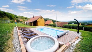 A swimming pool with lounge chairs, a hot tub, and a view of houses in the background. - Amazing home in Dragovanscak (Dragovanscak)