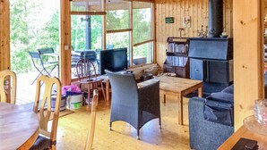 Interior acogedor de una cabaña con suelo de madera, chimenea, televisor y estantería.