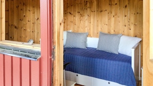 Una habitación con paneles de madera, una cama, almohadas y una ventana.