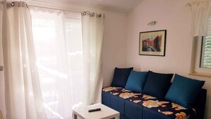Una sala de estar con un sofá, una mesita y un control remoto encima.