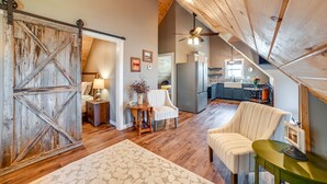 A spacious loft with a high ceiling, wooden floors, a sliding barn door, a dining area, and a kitchen with modern appliances. - Lovely Lakefront Apartment w/ Boat Ramp Access (Clifton)