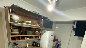 Eine kleine Küche mit Kühlschrank, Mikrowelle und Deckenventilator.