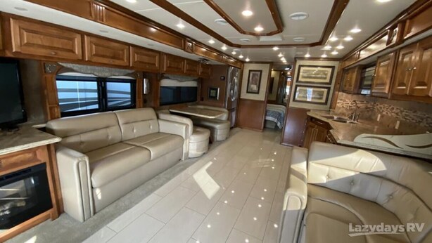 A spacious RV interior with a large seating area, a kitchen with wooden cabinets, and a television. - Enjoy your stay in luxury at Grange for PSU Tailgate, or our Private Lot w/Pool (Bellefonte)