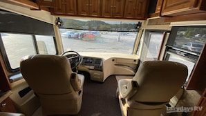 A recreational vehicle interior with two beige leather seats, a central control panel, and a view of a parking lot through the windows. - Enjoy your stay in luxury at Grange for PSU Tailgate, or our Private Lot w/Pool (Bellefonte)