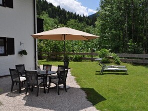Relax in a serene outdoor space with a round table and comfortable seating, shaded by a large umbrella.