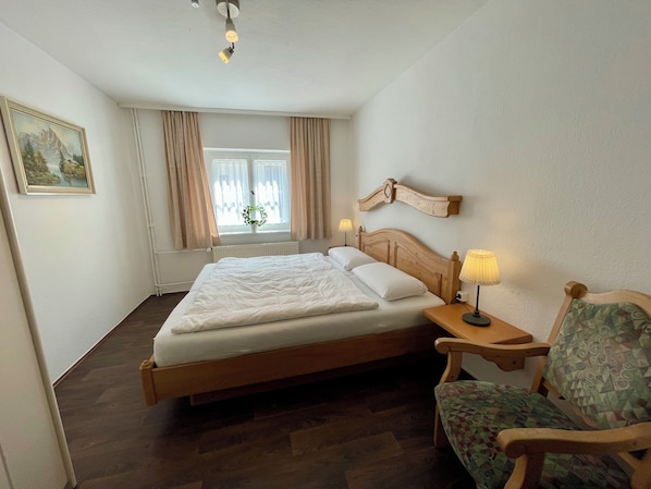 Relax in a spacious room with a large bed, bedside table, and comfortable chair.