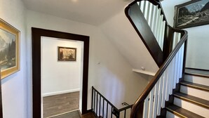 A staircase with a wooden handrail and white balusters, leading to a landing with a framed picture on the wall. - Forsthaus Fewo 10 OG (Reit im Winkl)
