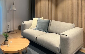 Un salon avec un canapé, une lampe, une petite table avec des bougies et une plante en pot.