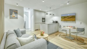 A modern kitchen with a central island, a dining area with a round table and chairs, and a living room with a sofa and a coffee table. - 1 bedroom amazing apartment in Tossens (Tossens)