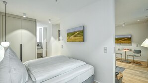 Une chambre moderne avec un lit, un téléviseur à écran plat et une vue sur un champ par la fenêtre.