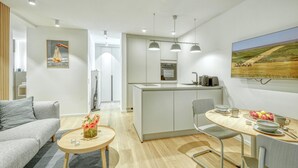 Une cuisine moderne dotée d’un îlot central, de luminaires suspendus et d’un coin repas avec une table dressée pour deux personnes.