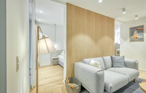A modern living room with a grey sofa, a wooden slat wall, and a hanging lamp. - 1 bedroom amazing apartment in Tossens (Tossens)