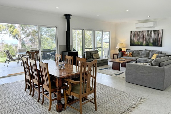 Open plan dining and lounge area with wood fire. Back deck access to forest and water views.