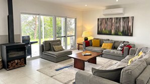 A living room with a fireplace, grey sofas, a coffee table, and a large window with a view of greenery.