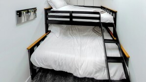 A bunk bed with a wooden frame and white bedding, a small shelf with a mirror, and a grey carpeted floor. - Superb bespoke lodge with four bedrooms sleeping up to ten people. (Laceby)