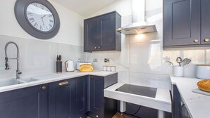A modern kitchen with dark cabinets, a white countertop, a built-in stove, and a wall clock. - Superb bespoke lodge with four bedrooms sleeping up to ten people. (Laceby)