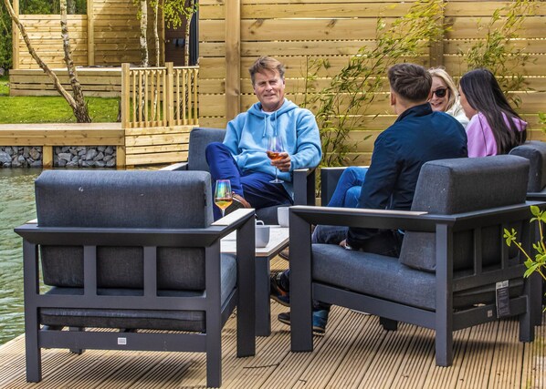 A deck with outdoor furniture, a wooden fence, and a body of water in the background.