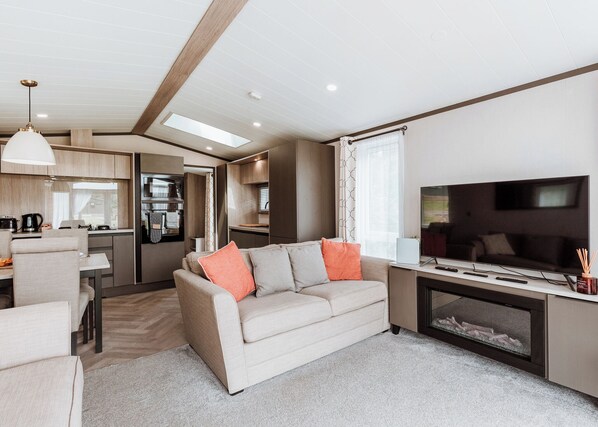 A modern RV interior with a living area, kitchenette, and a TV.