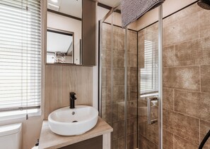 Une salle de bain avec un lavabo rond, un miroir et un espace douche doté de portes en verre.