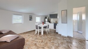 Ett kompakt bostadsutrymme med en säng, en matplats, ett litet kök och ett badrum.