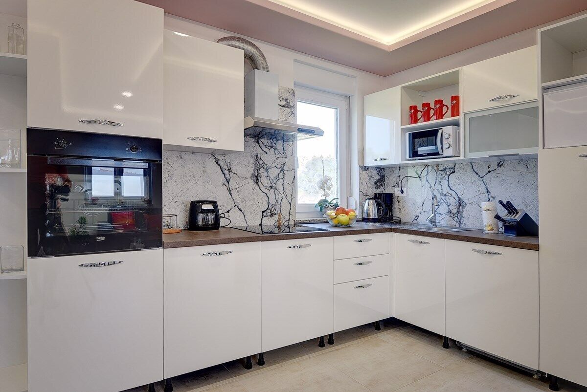 A modern kitchen with white cabinets, a built-in oven, and a microwave.