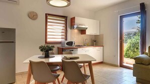 A modern kitchen with a dining area, a microwave, and a clock on the wall. - Holiday apartment with a beautiful garden for shared use (Vinkuran)