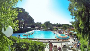 Ein Poolbereich mit mehreren Sonnenschirmen und Liegestühlen.
