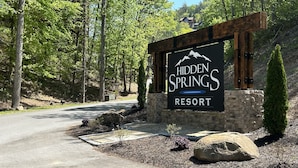 Un letrero para Hidden Springs Resort, con un muro de piedra y vigas de madera.