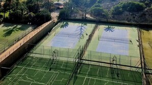 A tennis court with a scenic view of the sea and hills.