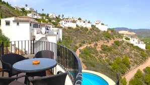A poolside area with a table and chairs, overlooking a hillside with white buildings and a clear sky. - Villa LOS TULIPANES in Monte Pego (Pego)